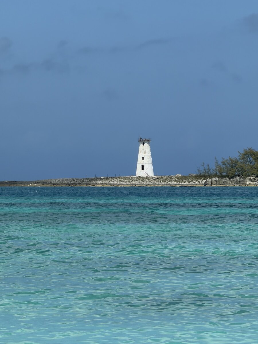 White lighthouse beyond clear turquoise water